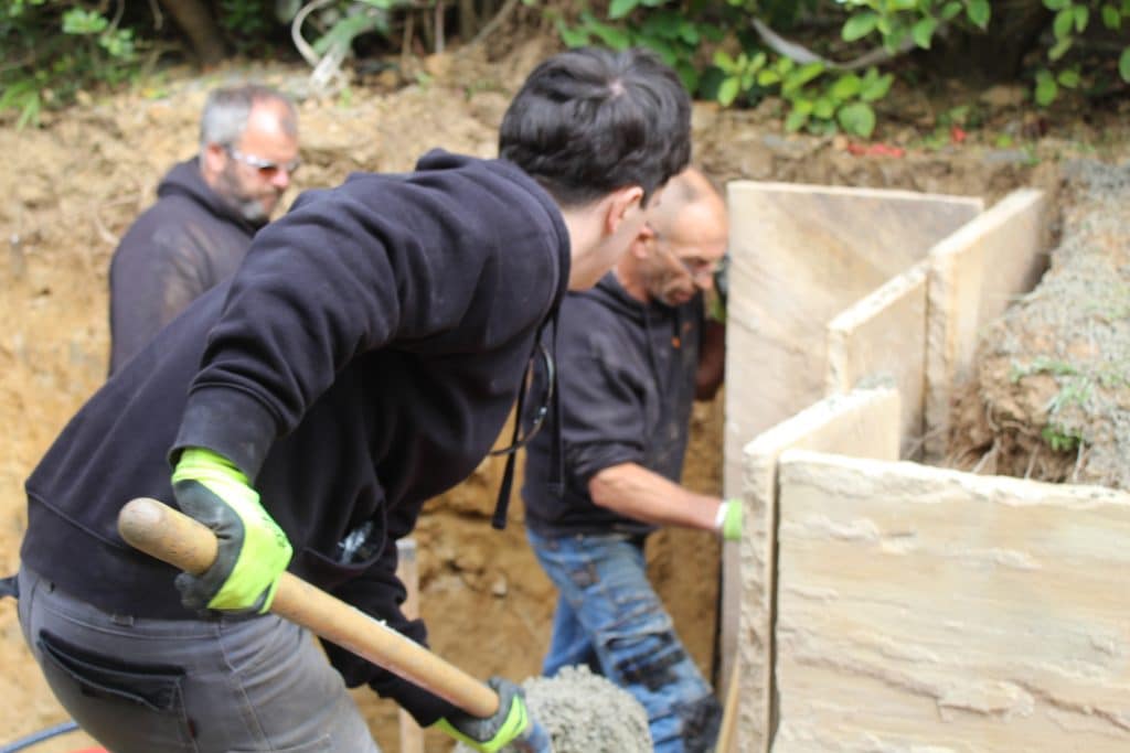 technicien verse du ciment avec pelle pour maintien dalles Kerra Terrassement avec collègues de travail